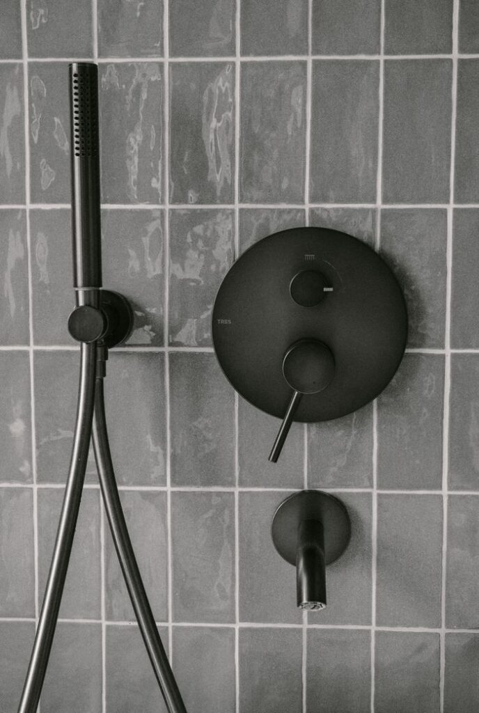 Stylish matte black shower fixtures on modern tiled wall, capturing minimalist bathroom design.
