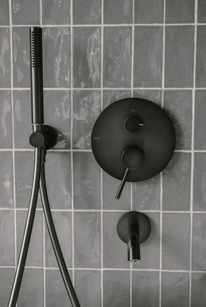 our-story Stylish matte black shower fixtures on modern tiled wall, capturing minimalist bathroom design.